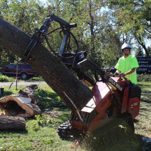 man using a machine to pick up a tree trunk
