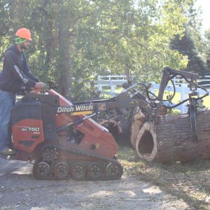 a machine that is used to pick up and moe large branches quickly. Man is moving a large tree trunk